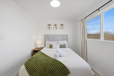 a bedroom with a bed with white sheets and a window at Cozy 2BR Retreat with Backyard Lounge in Aurora