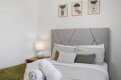 a bedroom with a bed with white sheets and pillows at Cozy 2BR Retreat with Backyard Lounge in Aurora