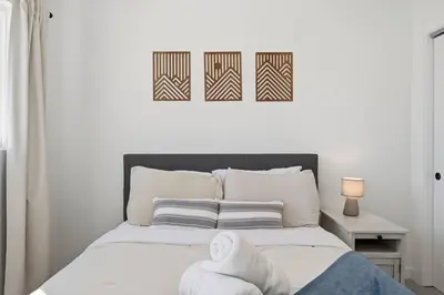 a bedroom with a bed with two pictures on the wall at Cozy 2BR Retreat with Backyard Lounge in Aurora