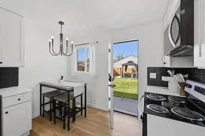 a white kitchen with a table and a stove at Cozy 2BR Retreat with Backyard Lounge in Aurora