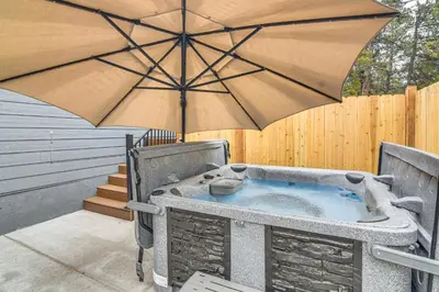 a hot tub with an umbrella on a patio at Hike and Fish Group Getaway with Hot Tub in Bailey! in Bailey
