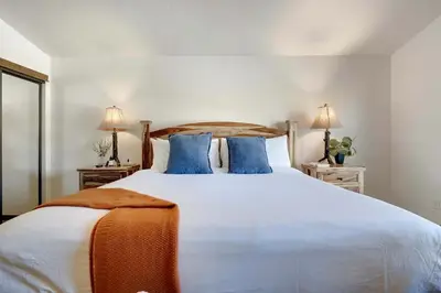 a bedroom with a large white bed with blue pillows at Serene Nordic-Inspired Lakeside Retreat with Panoramic Mountain Views Near Breckenridge, Dillon, Colorado in Dillon