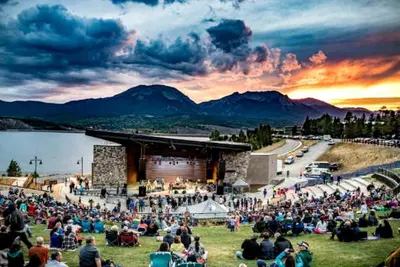 a crowd of people sitting in the grass at a concert at Serene Nordic-Inspired Lakeside Retreat with Panoramic Mountain Views Near Breckenridge, Dillon, Colorado in Dillon