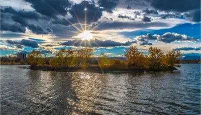 an island in the water with the sun in the sky at Spacious Denver Home with Private Rooftop Spa in Denver