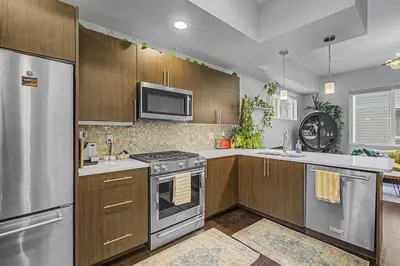 a kitchen with stainless steel appliances and wooden cabinets at Spacious Denver Home with Private Rooftop Spa in Denver