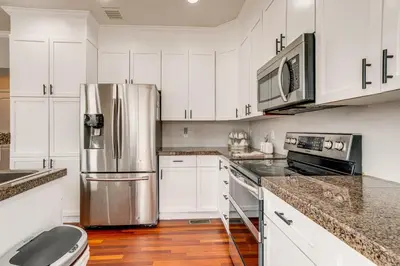 a kitchen with white cabinets and a stainless steel refrigerator at 6 Mi to Buckley Space Force Base Getaway with Patio in Aurora