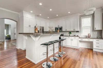 a kitchen with white cabinets and a counter with stools at 6 Mi to Buckley Space Force Base Getaway with Patio in Aurora