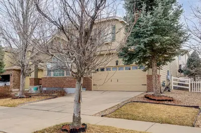 a house with two trees in front of it at 6 Mi to Buckley Space Force Base Getaway with Patio in Aurora