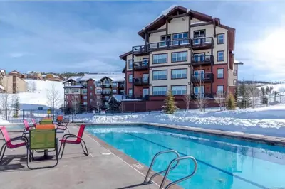 a apartment building with a swimming pool in the snow at Base Camp 402 condo in Granby
