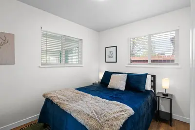 a bedroom with a blue bed and two windows at Private Home - Hot Tub, Game Room, Fire Pit, Fenced Yard in Westminster