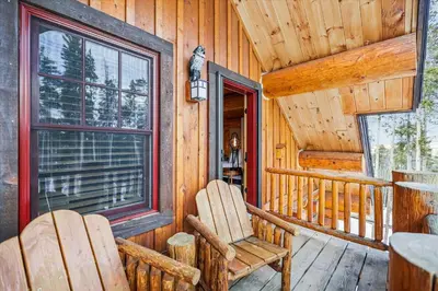 a porch of a cabin with two chairs and a window at Experience Fireside Retreat, a comfortable and secluded log home in Breckenridge, Hot Tub in Breckenridge