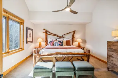 a bedroom with a bed and two ottomans at Experience Frisco Fling, a spacious house in the heart of Frisco with a hot tub and wooded views in Frisco