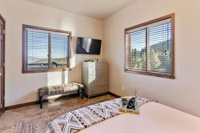 a bedroom with a bed and a dresser and windows at Family Mountain Getaway w Hot Tub and Amazing Views! Close to Hiking & Skiing in Idaho Springs