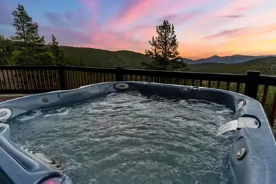 a hot tub on a deck with a sunset at Family Mountain Getaway w Hot Tub and Amazing Views! Close to Hiking & Skiing in Idaho Springs