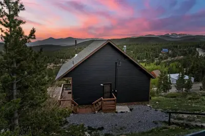 a black barn with a sunset in the background at Family Mountain Getaway w Hot Tub and Amazing Views! Close to Hiking & Skiing in Idaho Springs