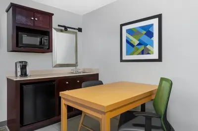 a kitchen with a wooden table and a microwave at Holiday Inn Express & Suites Wheat Ridge-Denver West by IHG in Wheat Ridge