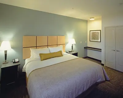 a large bed in a hotel room with two lamps at Candlewood Suites Fort Collins by IHG in Fort Collins