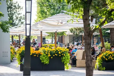a group of people sitting at tables under umbrellas at Hyatt House Denver Lakewood Belmar in Lakewood