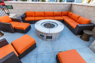 an outdoor seating area with orange chairs and a fountain at Hyatt House Denver Lakewood Belmar in Lakewood