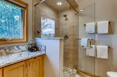 a bathroom with a glass shower and a sink at Frisco Cedar Cabin in Frisco