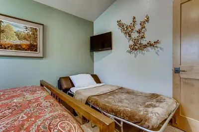 a room with two beds and a tv on the wall at Frisco Cedar Cabin in Frisco