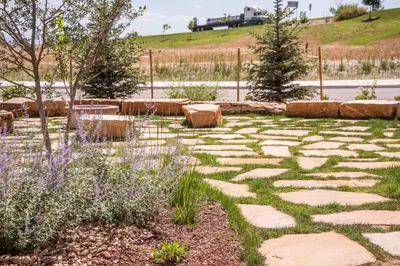 a garden with rocks and trees and a fence at Candlewood Suites Denver North - Thornton by IHG in Thornton