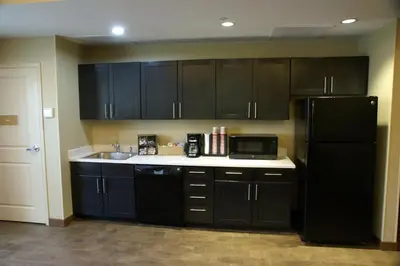 a kitchen with black cabinets and a black refrigerator at Candlewood Suites Denver North - Thornton by IHG in Thornton