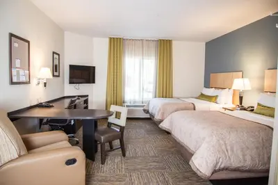 a hotel room with two beds and a desk at Candlewood Suites Denver North - Thornton by IHG in Thornton