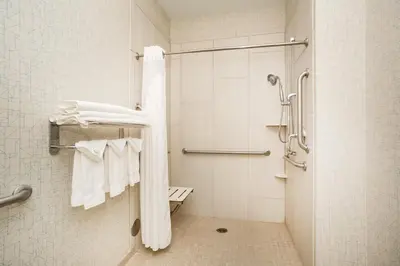 a bathroom with a shower with white towels at Holiday Inn Express & Suites Ft Collins by IHG in Fort Collins