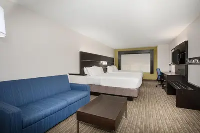 a hotel room with a bed and a blue couch at Holiday Inn Express & Suites Ft Collins by IHG in Fort Collins