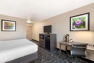 a hotel room with a bed and a desk with a computer at Best Western Greeley in Greeley