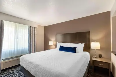 a hotel room with a large bed with blue pillows at Best Western Greeley in Greeley
