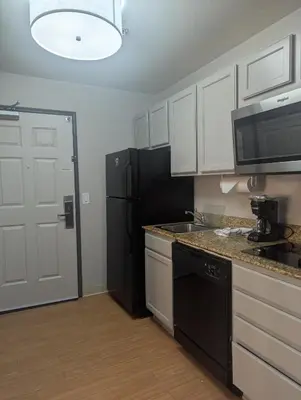 a kitchen with white cabinets and a black refrigerator at Candlewood Suites Loveland by IHG in Loveland