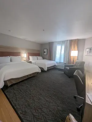 a hotel room with two beds and a couch at Candlewood Suites Loveland by IHG in Loveland