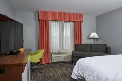 a hotel room with a bed and a couch and a television at Hampton Inn & Suites Denver/Highlands Ranch in Littleton