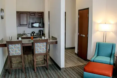 a room with a kitchen with a bar and chairs at Holiday Inn & Suites Denver Tech Center-Centennial by IHG in Centennial