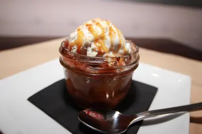 a dessert in a jar on a black plate with a spoon at Holiday Inn & Suites Denver Tech Center-Centennial by IHG in Centennial
