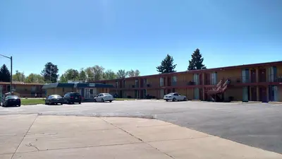 a building with cars parked in a parking lot at Essex House Motel in Littleton