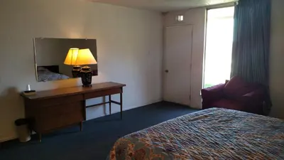 a hotel room with a bed and a desk with a mirror at Essex House Motel in Littleton