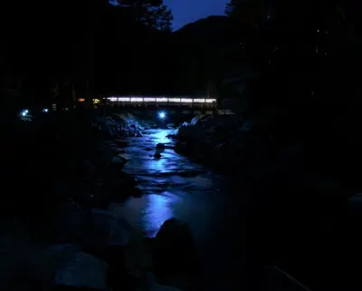 a night view of a river with a bridge in the background at The Inn on Fall River & Fall River Cabins in Estes Park