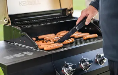 a man is cooking hot dogs on a grill at My Place Hotel-Loveland, CO in Loveland