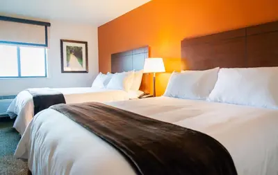 a hotel room with two beds and an orange wall at My Place Hotel-Loveland, CO in Loveland