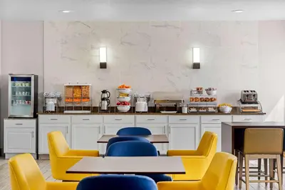 a restaurant with yellow chairs and tables in a kitchen at Comfort Suites Denver North - Westminster in Westminster