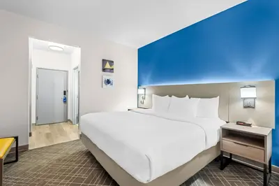 a large bed in a room with a blue wall at Comfort Suites Denver North - Westminster in Westminster