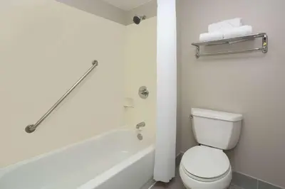 a bathroom with a white toilet and a bath tub at Days Inn & Suites by Wyndham Denver International Airport in Denver