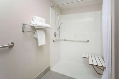 a bathroom with a shower and a toilet with towels at Days Inn & Suites by Wyndham Denver International Airport in Denver