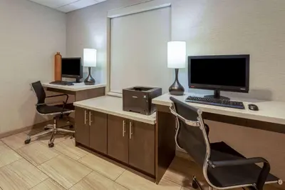 an office with a desk with a computer and two chairs at Days Inn & Suites by Wyndham Denver International Airport in Denver