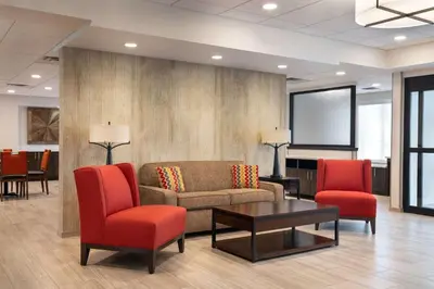a lobby with a couch and two red chairs at Days Inn & Suites by Wyndham Denver International Airport in Denver