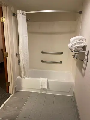 a white bath tub in a bathroom with a towel at Days Inn & Suites by Wyndham Denver International Airport in Denver