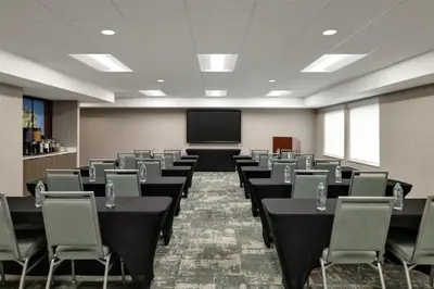 a conference room with tables and chairs and a screen at Homewood Suites by Hilton Denver West - Lakewood in Lakewood